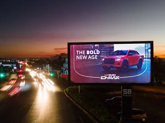 A roadside digital billboard advertising a pickup truck at sunset