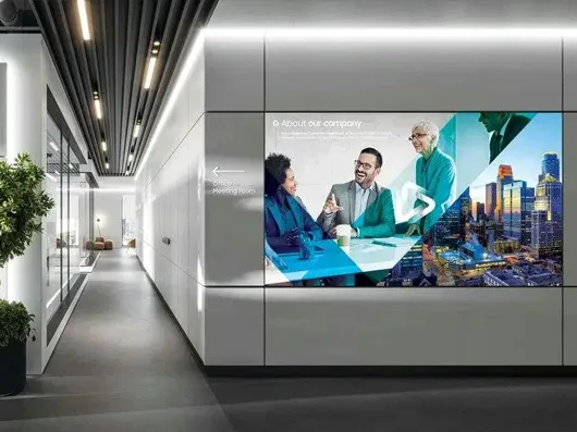 A video wall with company information wrapping the corner of an office corridor